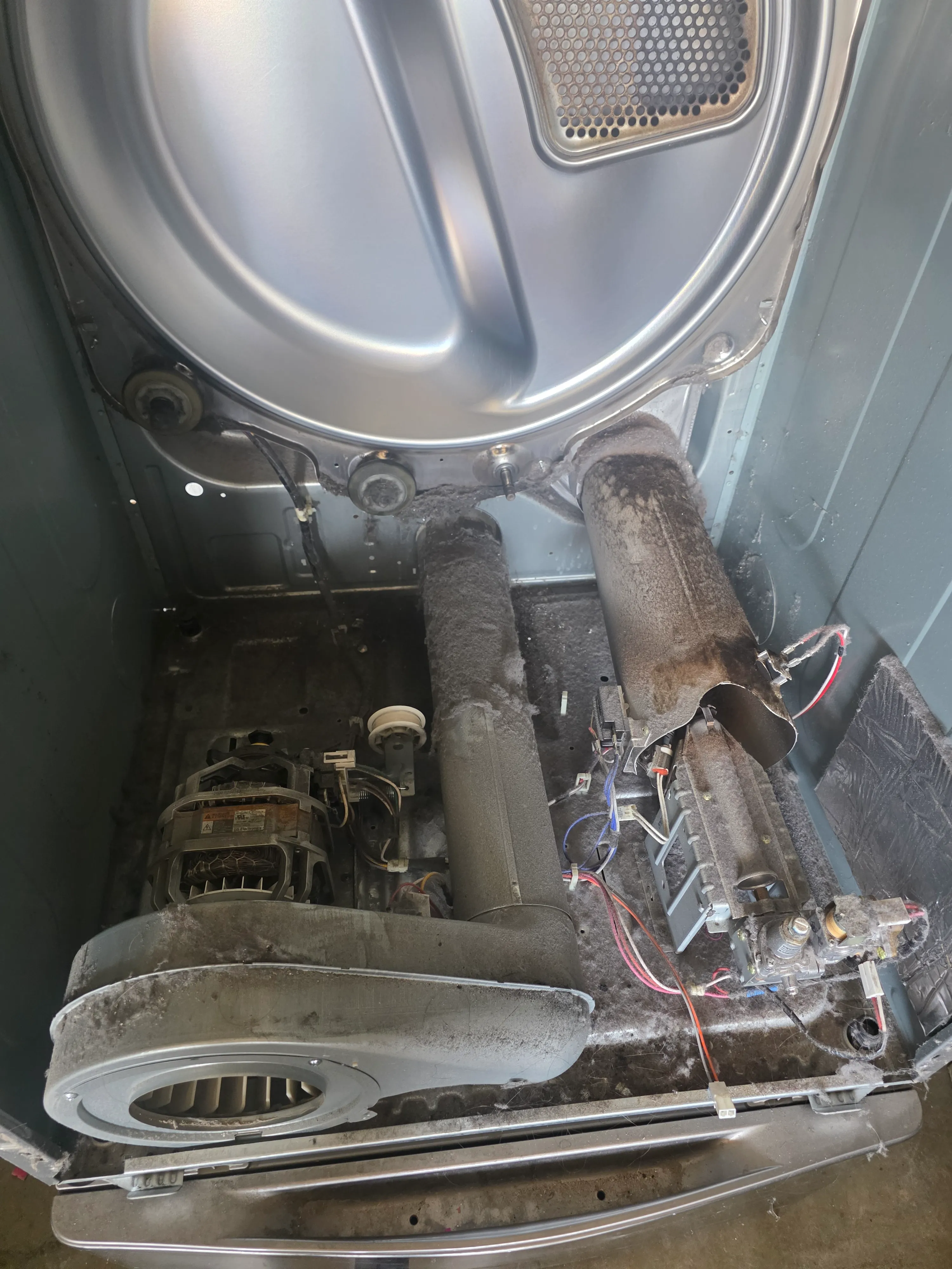 Dryer interior with heating element, motor, and blower exposed during repair